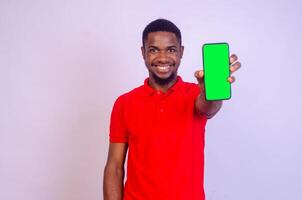 hermoso negro hombre muestra su teléfono pantalla mientras sensación contento y entusiasmado, publicidad concepto, atención en su cara foto