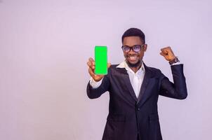 excited young black business man showing his phone screen to the camera and pointing to it photo