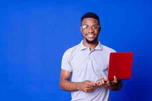 Young surprised african american man standing and using laptop computer photo