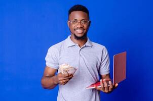 young african businessman holding a lot of money and using his laptop photo