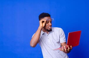 Young surprised african american man standing and using laptop computer photo