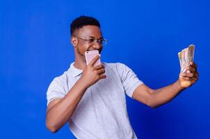 young african businessman holding a lot of money and using his phone photo