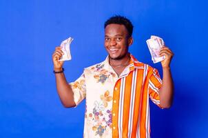 happy and excited young african man holding bundles of cash photo