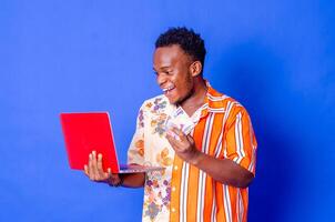 Portrait of young modern businessman standing holding laptop photo