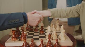 Draw in chess game. Players shake hands over chessboard. Draw in chess game. Players shake hands over chessboard. The grandfather and grandson finished the game. video