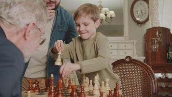 das Familie Theaterstücke Schach. das Vater ist glücklich und stolz von seine Sohn, Wer schachmatt seine Großvater. das Junge ordnet neu das Stücke beim das Schachbrett und Gewinnt. video