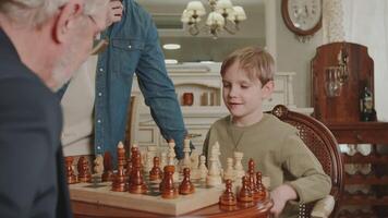 une garçon est en jouant échecs. réorganise le pièce et gagne. le père est fier de le sien fils, embrasser et étreindre lui dans joie. une famille passe-temps. video