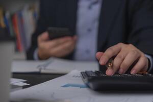 Businessman using calculator and accounting documents at desk with laptop computer. photo