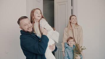Dad with his daughter in his arms. A young family inspects a new house. Mortgage. Vivid emotions. joyful smiles. video