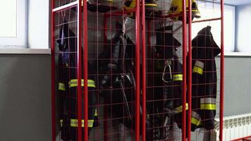 bombeiro capacetes e proteção casacos suspensão dentro a fogo estação. fogo equipamento video
