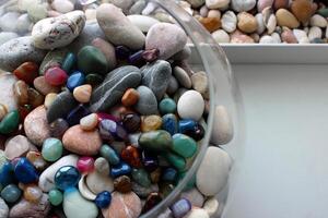 Round glass sphere filled with semi precious stones next to a box of sea pebbles and shells photo
