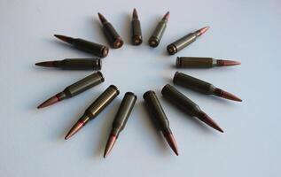 Bullets laid out in a circle shape on a white surface angle view photo