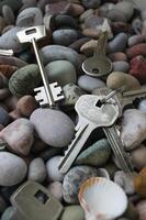 Bunches of keys and single keys are scattered in a mess on the stones vertical stock photo