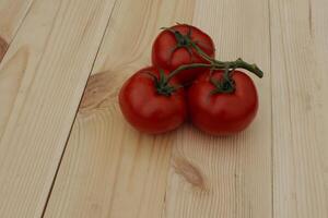 Ripe Juicy Tomatoes In A Bunch On A Wooden Boards photo