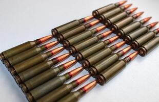 Live ammunition caliber 5.45 laid out eight in a rows on a white surface top view photo