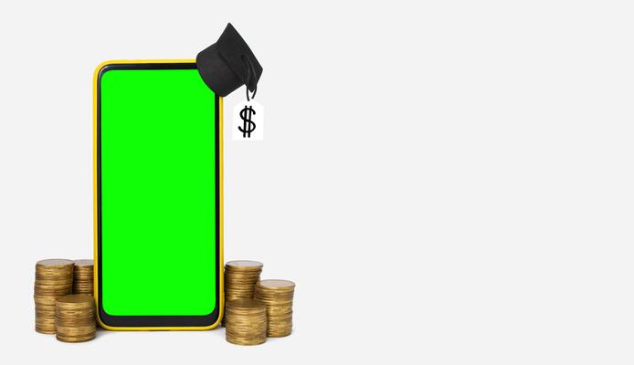 Online financial literacy and education concept. Graduation hat on smartphone and gold coins. Copy space