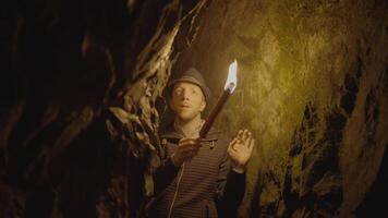 homme en portant une brûlant torche explorant forêt la grotte paysage dans foncé nuit video