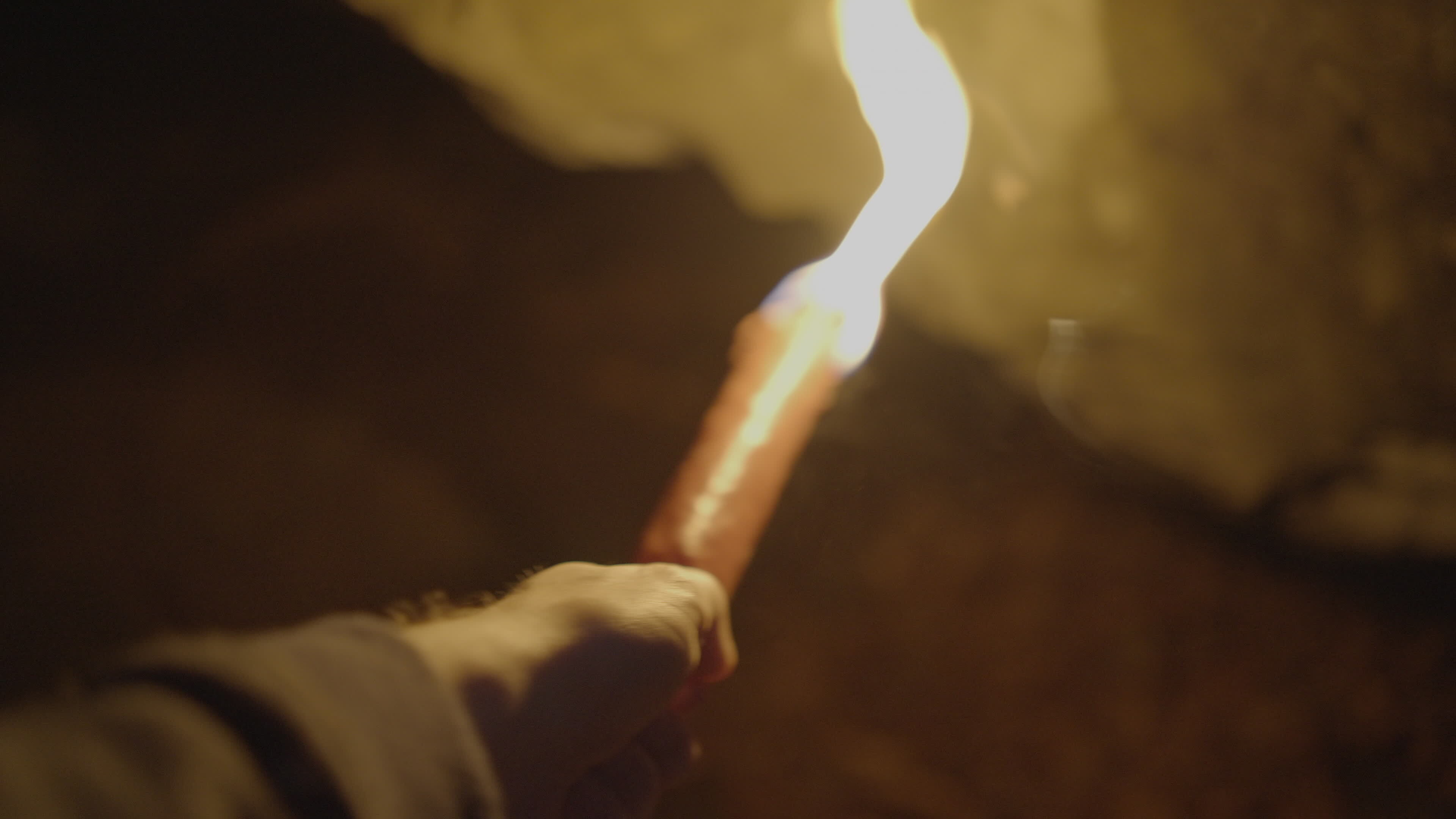 Person Holding Flaming Burning Torch Light In Stone Cave Forest At
