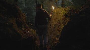 hombre participación un ardiente antorcha explorador bosque cueva paisaje en oscuro noche video