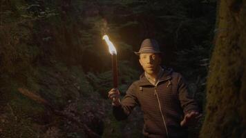 Man Holding A Burning Torchlight Exploring Forest Cave Landscape In Dark Night video