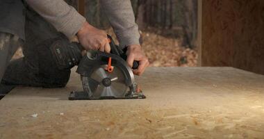 Close-up of a worker's hands using a circular saw to cut plywood. Construction of a new wooden house using frame technology. Carpentry and construction concept. photo