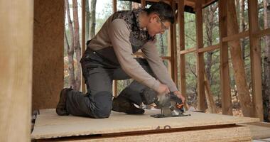 A worker uses a circular saw to cut plywood. Construction of a new wooden house using frame technology. The concept of building wooden houses. photo