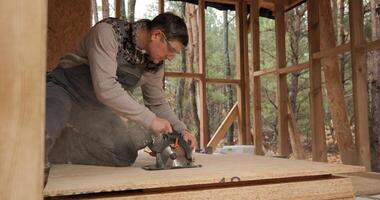 A worker uses a circular saw to cut plywood. Construction of a new wooden house using frame technology. The concept of building wooden houses. photo