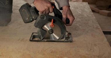 Close-up of a worker's hands using a circular saw to cut plywood. Construction of a new wooden house using frame technology. Carpentry and construction concept. photo