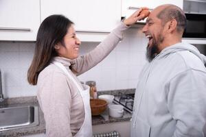 Woman tries to break an egg on her partner's forehead while he laughs. photo