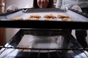 Woman putting the cookies she made into the oven. photo