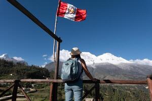 turista a un punto de vista con un peruano bandera observa el montaña llamado huascarán. foto