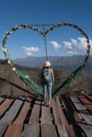 Tourist standing on a viewpoint next to a heart-shaped decoration. photo