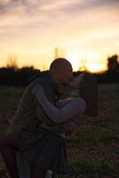 un hombre abrazos y Besos su Novia a puesta de sol en un natural ambiente. foto