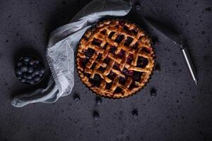 Homemade red fruit and blueberry pie placed on a dark background and viewed from above. photo