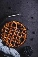 Homemade red fruit and blueberry pie placed on a dark background and viewed from above. photo