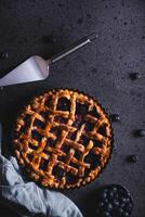 Homemade red fruit and blueberry pie placed on a dark background and viewed from above. photo