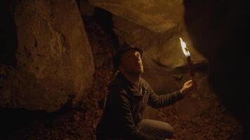 Man Holding A Burning Torchlight Exploring Forest Cave Landscape In Dark Night video