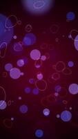 Vertical video - seamless motion background loop featuring gently moving purple, pink and blue bokeh spheres and rings.