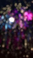 Vertical video - festive New Year celebration firework display background with defocused exploding colorful fireworks and shiny golden bokeh particles.