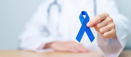 March Colorectal Cancer Awareness month, doctor with dark Blue Ribbon for supporting people living and illness. Healthcare, hope and World cancer day concept photo