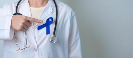 March Colorectal Cancer Awareness month, doctor with dark Blue Ribbon for supporting people living and illness. Healthcare, hope and World cancer day concept photo