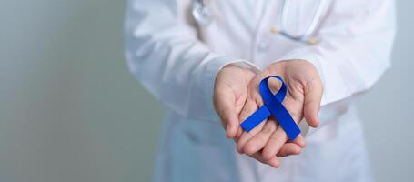 March Colorectal Cancer Awareness month, doctor with dark Blue Ribbon for supporting people living and illness. Healthcare, hope and World cancer day concept photo