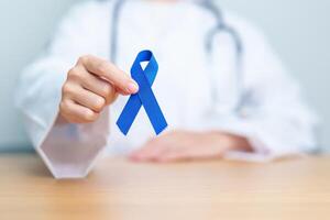 March Colorectal Cancer Awareness month, doctor with dark Blue Ribbon for supporting people living and illness. Healthcare, hope and World cancer day concept photo