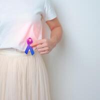 Woman holding Blue ribbon with having Abdomen pain. March Colorectal Cancer Awareness month, Colonic disease, Large Intestine, Ulcerative colitis, Digestive system and Health concept photo