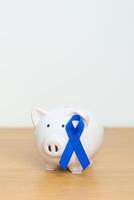 marzo colorrectal cáncer conciencia mes, Armada azul cinta con cerdito banco para apoyo enfermedad vida. salud, donación, caridad, campaña, dinero ahorro, fondo y mundo cáncer día concepto foto