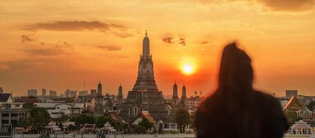 wat arun templo en atardecer, turistas disfrutar el ver a templo de amanecer cerca chao phraya río. tomar foto desde techo bar. punto de referencia y viaje destino en bangkok, Tailandia y Sureste Asia
