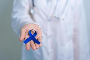 March Colorectal Cancer Awareness month, doctor with dark Blue Ribbon for supporting people living and illness. Healthcare, hope and World cancer day concept photo