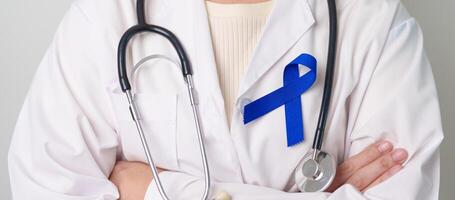 March Colorectal Cancer Awareness month, doctor with dark Blue Ribbon for supporting people living and illness. Healthcare, hope and World cancer day concept photo