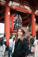 turista mujer visitar sensoji templo o asakusa Kannon templo es un budista templo situado en asakusa, tokio Japón. japonés frase en rojo linterna medio trueno puerta. foto