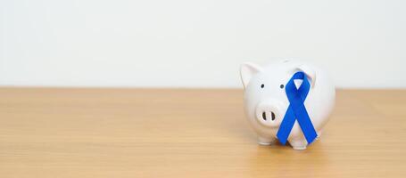 March Colorectal Cancer Awareness month, Navy Blue Ribbon with Piggy Bank for support illness life. Health, Donation, Charity, Campaign, Money Saving, Fund and World cancer day concept photo